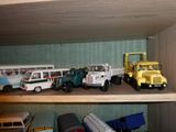 de nombreux camions et bus miniatures posés sur une étagère dans une pièce