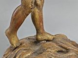 bronze figurine of a boy holding a bird on a rock