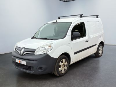 La camionnette blanche est garée dans une grande pièce au sol noir.