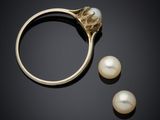 a close up of a ring and two pearls on a black surface