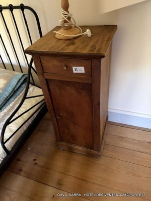 une petite table sur laquelle est posée une lampe, à côté d'un lit