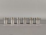six silver shot glasses lined up in a row