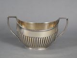 a silver plated bowl with handles and handles on a gray surface