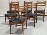 quatre chaises en bois avec des assises en cuir noir dans une pièce