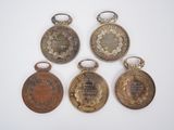 four medals of various sizes and shapes are displayed on a white surface