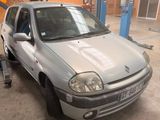 La voiture argentée est garée dans le garage, la porte ouverte.