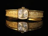 an image of a gold wrist watch with roman numerals and roman numerals