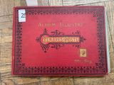 a red book sitting on top of a wooden floor next to a pair of scissors