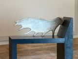 a bench with a metal sculpture on it in a room