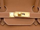 the handle of a brown leather handbag with a gold lock