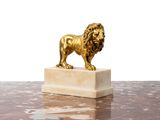 statue of a golden lion on a marble base on a table