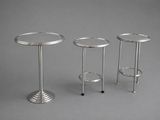 three silver metal side tables on a grey background