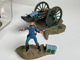 two figurines of a man with a gun and a cart