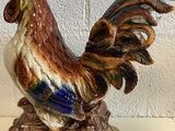 une figurine représentant un coq debout sur un rocher