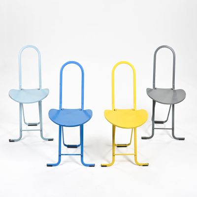 trois chaises de couleurs différentes sont disposées côte à côte sur une surface blanche
