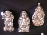 three silver figurines of santa claus, santa claus, and santa claus