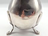 a silver vase on a stand with a mirror in it