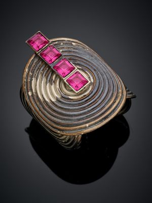 un gros plan d'une bague ornée de pierres roses sur un fond noir