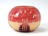 un vase rouge et jaune posé sur une surface blanche