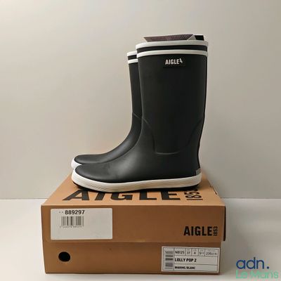 black and white rubber boots on top of a box on a white surface
