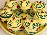 une assiette jaune sur laquelle sont disposés plusieurs petits cupcakes