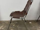 a brown leather chair sitting in front of a white wall