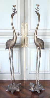 deux flamants roses en métal placés l'un à côté de l'autre sur un plancher en bois