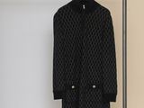 a black coat hanging on a clothes rack next to a white wall