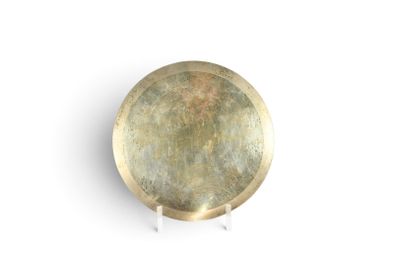 une assiette dorée posée sur une surface blanche, avec un fond blanc