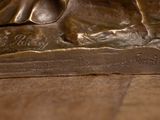 a bronze statue of a dog laying on a table