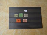 une feuille de papier noir sur laquelle sont apposés des timbres de différentes couleurs