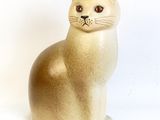 beige cat figurine sitting on a white surface with a white background