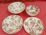 four white and brown plates sitting on top of a red cloth