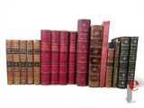 several old books are lined up in a row on a white surface