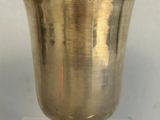 a silver vase sitting on a glass stand on a table