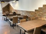 tables and chairs in a restaurant with a brick wall in the background