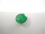 a green emerald stone sitting on top of a white surface
