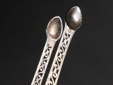 a close up of a pair of silver spoons on a black surface