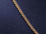 a close up of a gold chain on a black leather surface