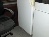a white refrigerator and a black chair in a small kitchen