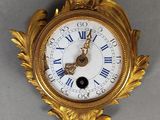 une horloge dorée avec un cadran blanc et un oiseau dessus