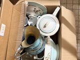 a cardboard box full of tea cups and saucers on the floor