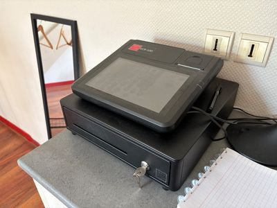 une photo d'un terminal de paiement électronique noir posé sur un comptoir
