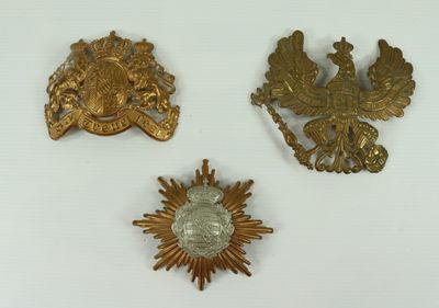 three gold brooches of various shapes and sizes on a white surface