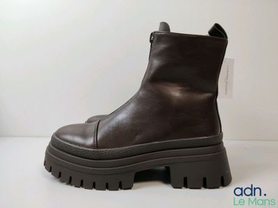 des bottines en cuir marron à semelles en caoutchouc, posées sur un fond blanc