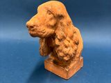 une vieille statue représentant un chien assis sur un bloc de bois