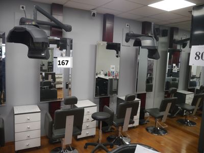 une photo d'un salon de coiffure avec des fauteuils et des miroirs