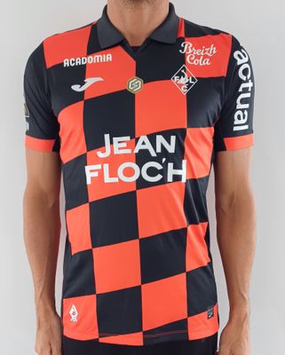 Cet homme porte un t-shirt rouge et noir et un short noir.