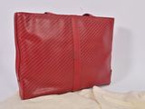 red leather handbag on a bed with a white sheet