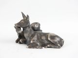 une statue représentant un chien couché sur une surface blanche